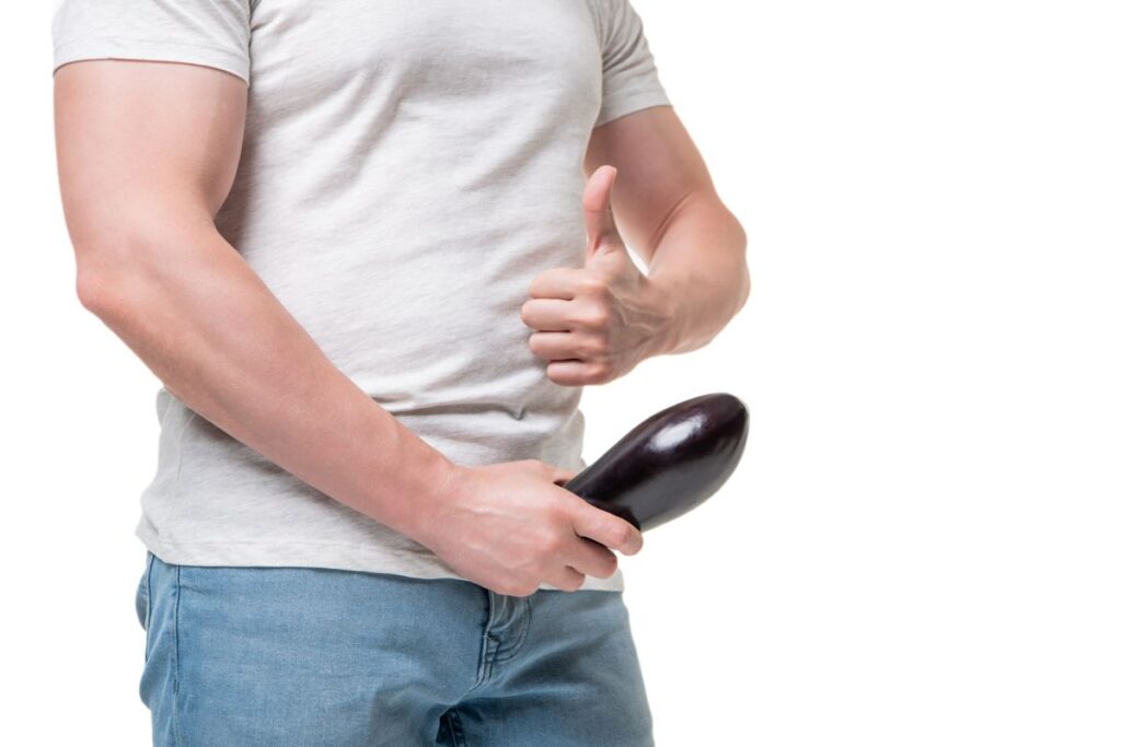 Homem com segura uma berinjela em posição sugestiva, representando simbolicamente o desejo de saber com engrossar o pênis