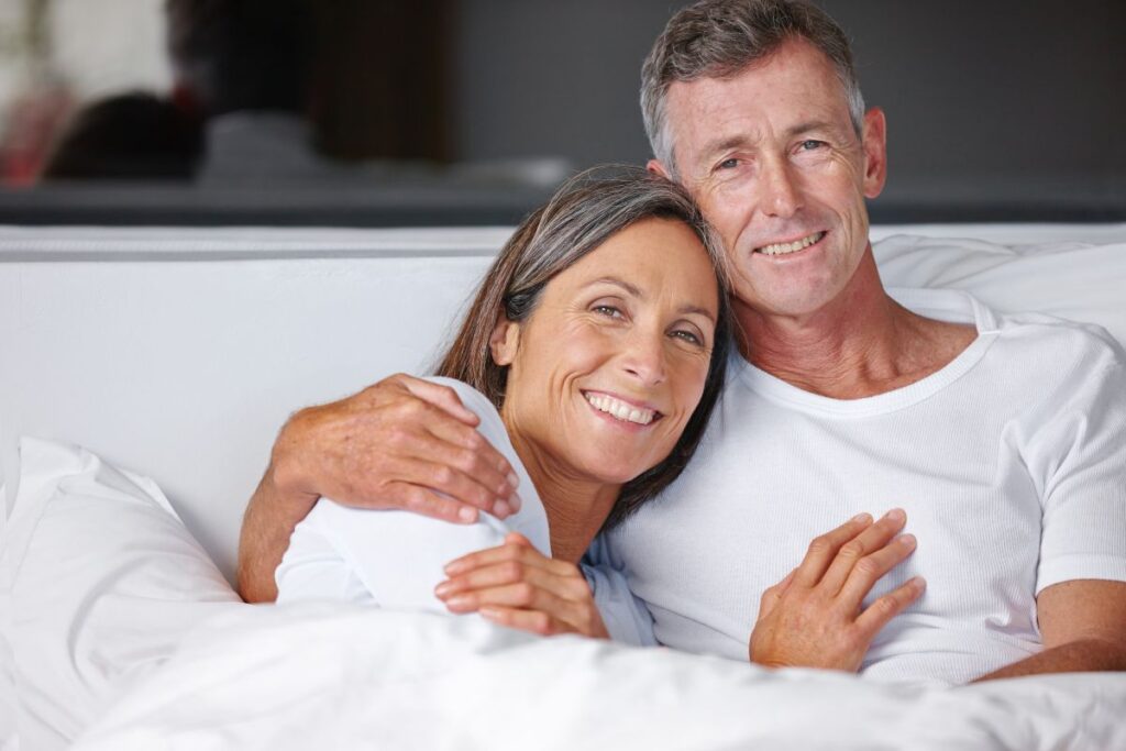 Casal em momento de intimidade na cama, demonstrando recuperação da vida sexual após implante de prótese peniana e fortalecimento emocional do relacionamento conjugal.