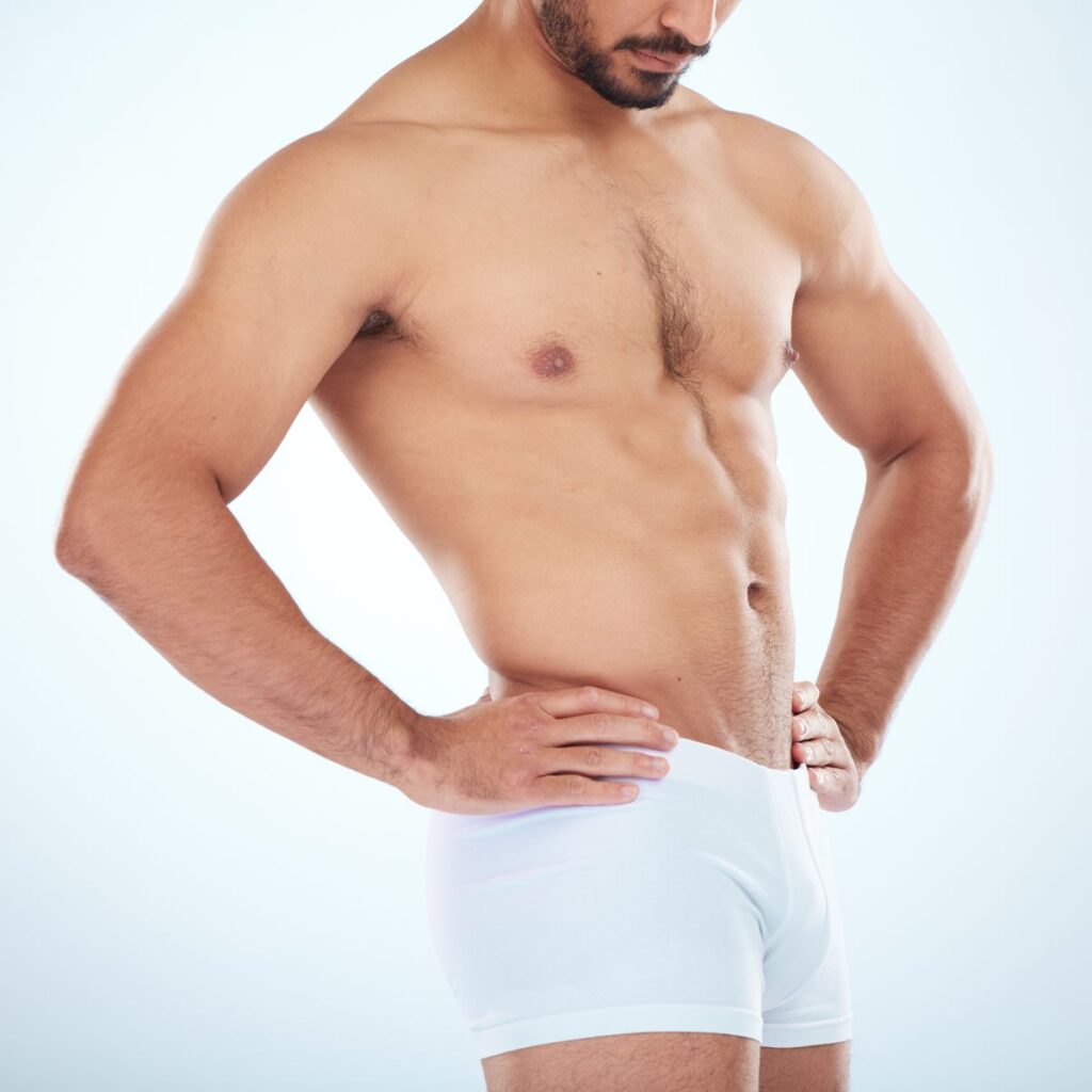 Homem adulto usando roupa íntima branca observando a região íntima, ilustrando o tema harmonização peniana valor e procedimentos de estética íntima masculina.